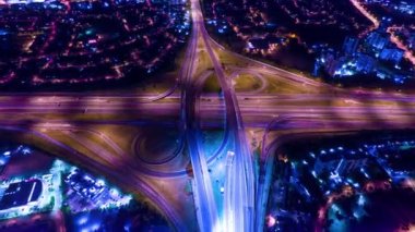 Top night view of car traffic at intersection lane and buildings time lapse. Long exposure of urban cityscape at night. Modern city in Canada full of night lights from energy and power. Timelapse.