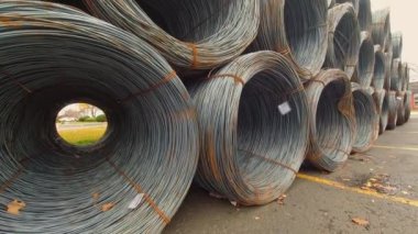 Stowage of metal wire rods in coils near manufacturing. Bundle of industrial metal wire coils ready for processing. View of made steel billets urban area of steel factory manufacturing.