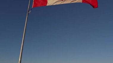 Happy Canadian citizen patriot concept. Canadian flag at wind, blue cloudy sky and golden hour sun.