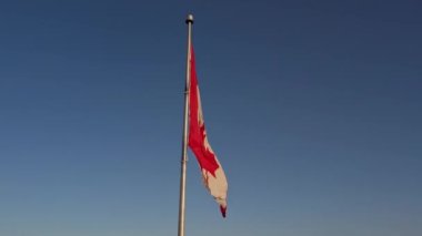 Happy Canadian citizen patriot concept. Canadian flag at wind, blue cloudy sky and golden hour sun.