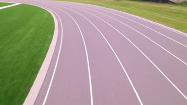 Açık hava spor stadyumundaki koşu pisti manzarasının üzerinde. Atletizm stadyumu ve koşu pisti boyunca yarışan atlet POV. Rekabet sporları ve şampiyon sıkı çalışma.