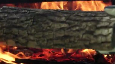 Adam büyük odunları ateş için ızgara bölümüne koymuş. Hafta sonları barbekü kömürü ve ızgara için büyük ateş yakılır. Büyük kamp ateşi yakın..