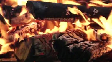 Barbekü ızgara bölümünde odun kütükleri ve kömürle yanan küçük bir yer. Gerçek odunla ızgarada ateş yanıyor. Ahşap kütüklerin üzerinde parlak bir alev var. Yaz tatili ve kamp..