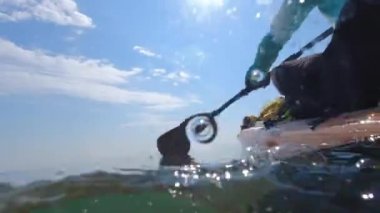 Split view of woman rowing on stand up paddle board at azure sea, underwater and above water of SUP board and paddle at warm summer morning. Travel destination and vacation holidays.