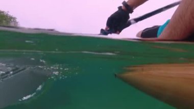 Split view of woman rowing on stand up paddle board at azure sea, underwater and above water of SUP board and paddle at warm summer morning. Travel destination and vacation holidays.