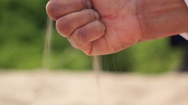 Oyuncu kadının eli bir avuç sarı deniz kumu fırlatıyor. Yaz tatilinde kaygısız kız yumuşak kumlu sıcak ve çarpıcı tropikal plajda oynar. Kadın sıcak kumun parmaklarının arasına düşmesine izin verir..