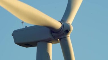 Aşağıdan rüzgar türbini güç istasyonuna yakın çekim. Çevre mühendisliği ve yenilenebilir enerji. Akşamları mavi gökyüzü ve altın saatinde telefoto lensleriyle rüzgâr değirmenlerinin manzarası