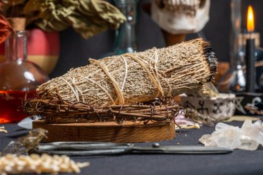 Bilge büyücülük aromaterapisi ve lekeleme, seçici odaklanma. Ruhsal ve arındırıcı doğaüstü bilim ve okült bilgi. Sihirli aletlerle çevrili dumanlı adaçayı. Sihir ritüeli icra.