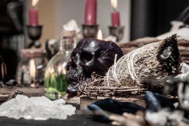 Bilge büyücülük aromaterapisi ve lekeleme, seçici odaklanma. Ruhsal ve arındırıcı doğaüstü bilim ve okült bilgi. Sihirli aletlerle çevrili dumanlı adaçayı. Sihir ritüeli icra.