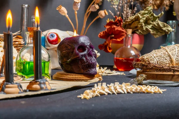 stock image Human skull candle selective focus, arranged with black candles and spell potion vials on witchcraft background. Magic tools and items. Occult and esoteric concept. Magic chemistry and witch craft.