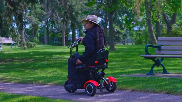Videographer or photographer with mobility disability taking a photo of nature and enjoying spring. Cinematic shot of multiethnic independent semi professional content creator on the mobility scooter
