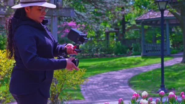 中年女性摄影师或摄影师 手里拿着相机装置 拍摄自然森林公园里的内容 女性自然摄影师在花园用相机拍照 — 图库视频影像