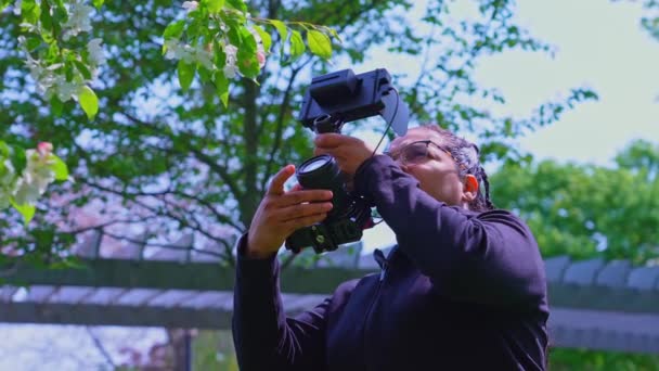 多族裔女摄影师站在室外 配有半专业的摄像机和视频监视器 自然中的相机女性自由拍摄场景 — 图库视频影像