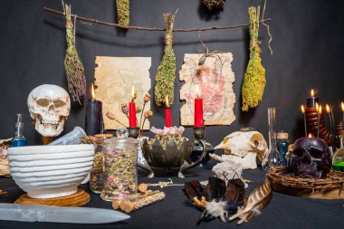 Büyülü eşyalarla yapılan cadı ayini. Sihirli semboller ve aletler. İçinde kara büyü mumları, kuru otlar, hayvan kemikleri ve iksir şişeleri olan bir kompozisyon. Cadılar Bayramı konsepti.