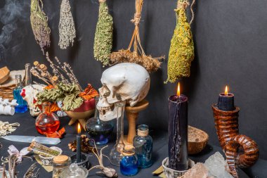 İnsan kafatasları büyü ritüeli. Kara büyü bağlantılı nesneler ve araçlar. Cadı simyacı ve sihirbaz imajının gotik cadılar bayramı tarzında bir hayat. Siyah yanan mumlarla çevrili.