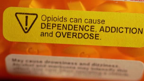 警告ステッカー付きの処方箋ボトルは オピオイドは依存症 依存症 過剰摂取を引き起こす可能性があります オピオイドは 一般的に様々なタイプの慢性疼痛を軽減するために処方されます — ストック動画