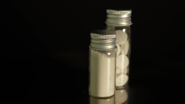 ガラス瓶に貯蔵された粉末状の違法薬物は 薬物乱用を示しています オピオイドとフェンタニルを含む継続的な危機 コンテナに置かれたヘロインまたは粉砕された酸素コドン — ストック動画