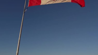 Happy Canadian citizen patriot concept. Canadian flag at wind, blue cloudy sky and golden hour sun.