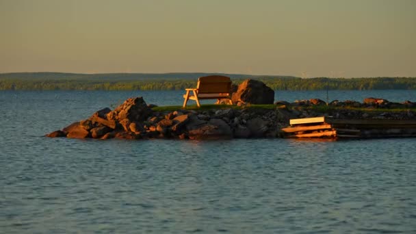 マンコス湖の小さなボート湾 黄金の時間の日没の夕暮れで空のベンチのロマンチックな眺め 静かな水の静かな魅力に囲まれています ゴールデンライトはその魅惑的な光 ロマンチックな雰囲気をキャスト — ストック動画
