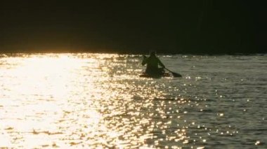 Manitou Gölü 'nde yoga yapan bir kadın. Zihin-beden bağlantısını ve altın renkli günbatımını geliştirmek. Denge, odaklanma ve istikrar kavramı, zen deneyimi. Ağır çekimde süzülen.