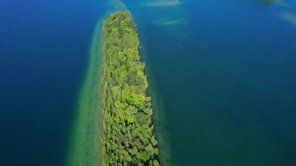 湖のきれいな水に囲まれたリトリートコテージまたはキャビン付きの小さな島 北米の晴れた夏の日 カナダの有名な観光客の休暇のルート — ストック動画