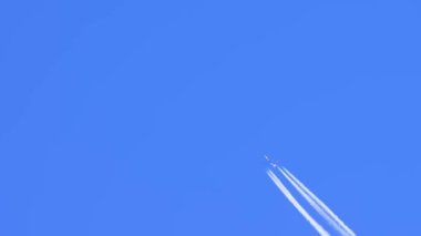 Mavi gökyüzünde parlak beyaz iz bırakan bir jet uçağı. Uçak buharı, Contrails, Chemtracils, ya da Yoğunlaşma Yolu, motorlardan gelen havacılık uçağı emisyonları. Uçaktan CO2 karbondioksit.