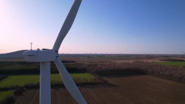 Arka planda rüzgar türbinleri, elektrik santrali çiftlikleri olan bir manzara. Çevre mühendisliği ve yenilenebilir enerji. Yel değirmenlerinin hava manzaralı türbinleri altın saat günbatımında akşam.