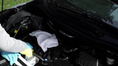 Close up of a women hand washing and wiping the car with cloth. Vehicle wash and cleaning the car engine compartment or car detailing services concept.