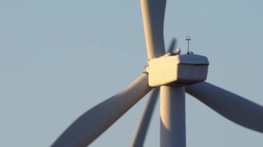 Aşağıdan rüzgar türbini güç istasyonuna yakın çekim. Çevre mühendisliği ve yenilenebilir enerji. Akşamları mavi gökyüzü ve altın saatinde telefoto lensleriyle rüzgâr değirmenlerinin manzarası
