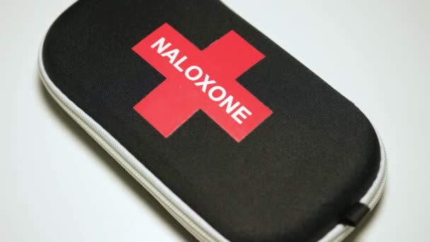 緊急袋に書かれたNaloxoneと赤十字には オピオイド薬の過剰摂取の回復に使用される薬が含まれています 過剰摂取キットのナス薬 トロント オンタリオ カナダ 2024 — ストック動画