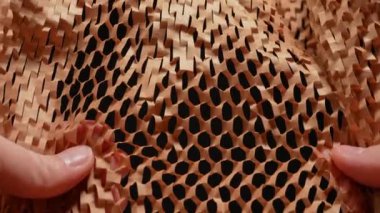 Paketler için eller kırışıyor ve yırtılıyor. El yapımı kahverengi bal peteği ambalaj kağıdı. Ağır çekimde buruşmuş el işi kağıtları. Geri dönüştürülmüş kağıt. Hediyeleri paketlemek için ambalaj ve dekorasyon kağıdı.