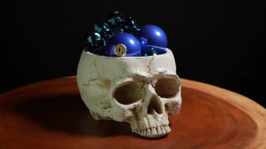 Noel oyuncakları taşıyan gotik insan kafatası. Karanlık huysuz gotik Noel kutlaması. İnsan kafası kara kavram.