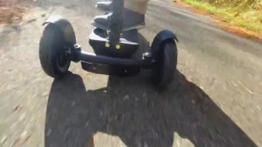 Motorlu scooter kullanan kişi işini ve ayak işlerini yapıyor. Eğlence amaçlı elektrikli araç ön taraftan hareket ediyor. Ekoloji, ulaşılabilirlik ve kolaylık kavramı.