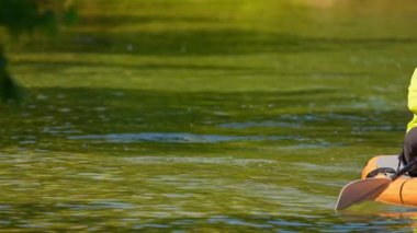 Can yeleği giymiş bir kadın ve göl suyunda spor yaparken. Güneşli yaz gününde kürek sporu ve kürek sporu. Kuzey Amerika, Kanada.