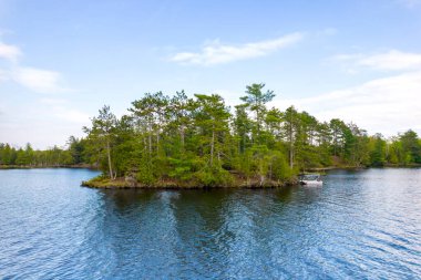 Turizm tatili ve macera havası. Amerika 'nın kuzey keşfi. Köknar ağaçlarıyla dolu küçük bir adaya demirlenmiş şişme bot. Kırsal kır evi göl suları. Destansı manzara sakin sular. 