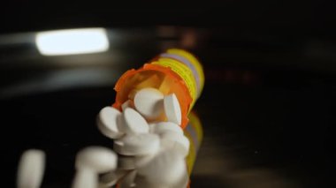 Reçeteli haplar şişeden yavaş çekimde masaya düşer. Farmasötik opioid Amerika 'da ağrı kesici krizi. Uyuşturucu bağımlılığı, aşırı dozda bağımlılığa yol açar. Makro yakın çekim.