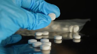 Mavi eldivenli polis dedektifi vakum torbasında bulunan yasadışı uyuşturuculara el koydu. Adli tıp suç bilimleri. Polis tarafından ele geçirilen haplar. Suç mahalli ve kanıt.