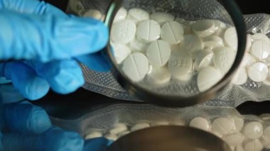 Mavi eldivenli polis dedektifi vakum torbasında bulunan yasadışı uyuşturuculara el koydu. Adli tıp suç bilimleri. Polis tarafından ele geçirilen haplar. Suç mahalli ve kanıt.