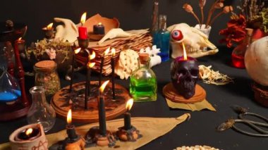 İnsan kafatası mumu seçici odak noktası, siyah mumlar ve büyü arkaplanındaki büyü iksiri şişeleriyle düzenlenmiş. Sihirli aletler ve eşyalar. Esrarengiz ve esrarengiz bir kavram. Sihirli kimya ve cadı zanaatı.