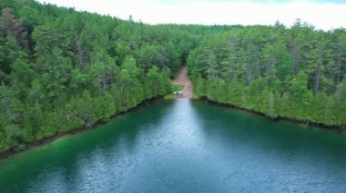 Ontario, Kanada 'daki doğal göl manzarası, Crown arazisi. Yoğun çam ormanları ve uzak tehlikeli rotalarla çevrili resimli kayalık turkuaz mavi göl. Sakin suyun destansı drone görüntüsü.