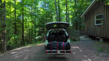 Kanada Ontario, Ontario 'daki Silent Lake Provincial Park' taki kulübenin yanında kamp bagajı ve kargo taşıyıcısı açık. Modern hatchback SUV araç açık kargo alanı. Seyahat araba tatili konsepti