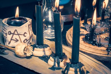 Kara büyü mumları büyücülük kompozisyonu. Sihirli ayin şeytani aletler ve eşyalar. Cadılar Bayramı ve okült kara büyü ritüeli hayali. Karanlık ve korkutucu atmosferde ayin sahnesi.