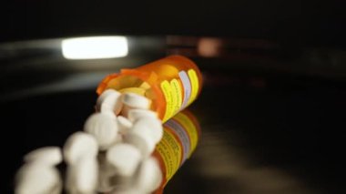 Reçeteli haplar şişeden yavaş çekimde masaya düşer. Farmasötik opioid Amerika 'da ağrı kesici krizi. Uyuşturucu bağımlılığı, aşırı dozda bağımlılığa yol açar. Makro yakın çekim.
