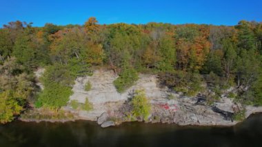 Trent Nehri suları ve turuncu ağaçlı kayalık duvarlar Campbellford 'daki Ranney Gorge Askı Köprüsü yakınlarında sonbahar manzaralı. Trent Nehri Ontario, Kanada 'daki Rice Gölü' ne bağlandı.