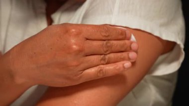 Kadın, ilacı enjekte ettikten sonra omzunu temizlemek için pamuk ve alkol kullanıyor. Kadın eli, mevsimsel aşılardan sonra dezenfekte oluyor..