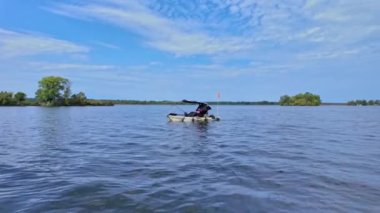 Yaz macerası sırasında gölde kano üzerinde kano sürmek, seyahat konsepti. PDL Drive balıkçı kanosu ve balıkçı teknesi gölde balık tutarken sürükleniyor. Kanoda balık tutmak..