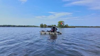 Gölde çubuklarla kano süren bir kadın, balık tutuyor. Balıkçı kadın güneşli yaz gününde gölde balık pedalı PDL kayığında kano tutuyor ve kano tutuyor. Kano balıkçılığı yaz sporları.