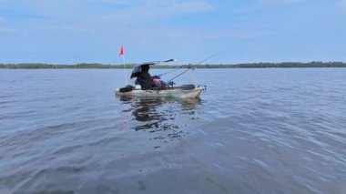 Gölde çubuklarla kano süren bir kadın, balık tutuyor. Balıkçı kadın güneşli yaz gününde gölde balık pedalı PDL kayığında kano tutuyor ve kano tutuyor. Kano balıkçılığı yaz sporları.