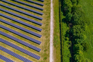 Çiftlikteki büyük güneş panellerine ve aydınlık yaz gününe bakın. Güneş pili santralinin yeniliği ve karbon ayak izini ve çevresel etkiyi azaltma teknolojisi.