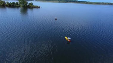 Kano balıkçılarının ve balıkçıların destansı hava manzarası gölün tadını çıkarırken kanoda balık tutuyor ve yazın gölün ortasında fotoğraf çekiyor. Balıkçı kanosu. Mavi gökyüzü ve bulutlar arka plan.